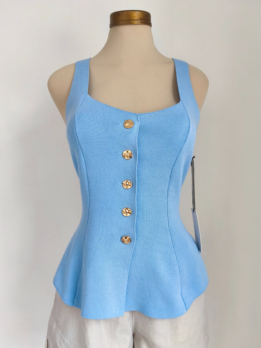 Blusa baby blue sin mangas con botones dorados y peplum