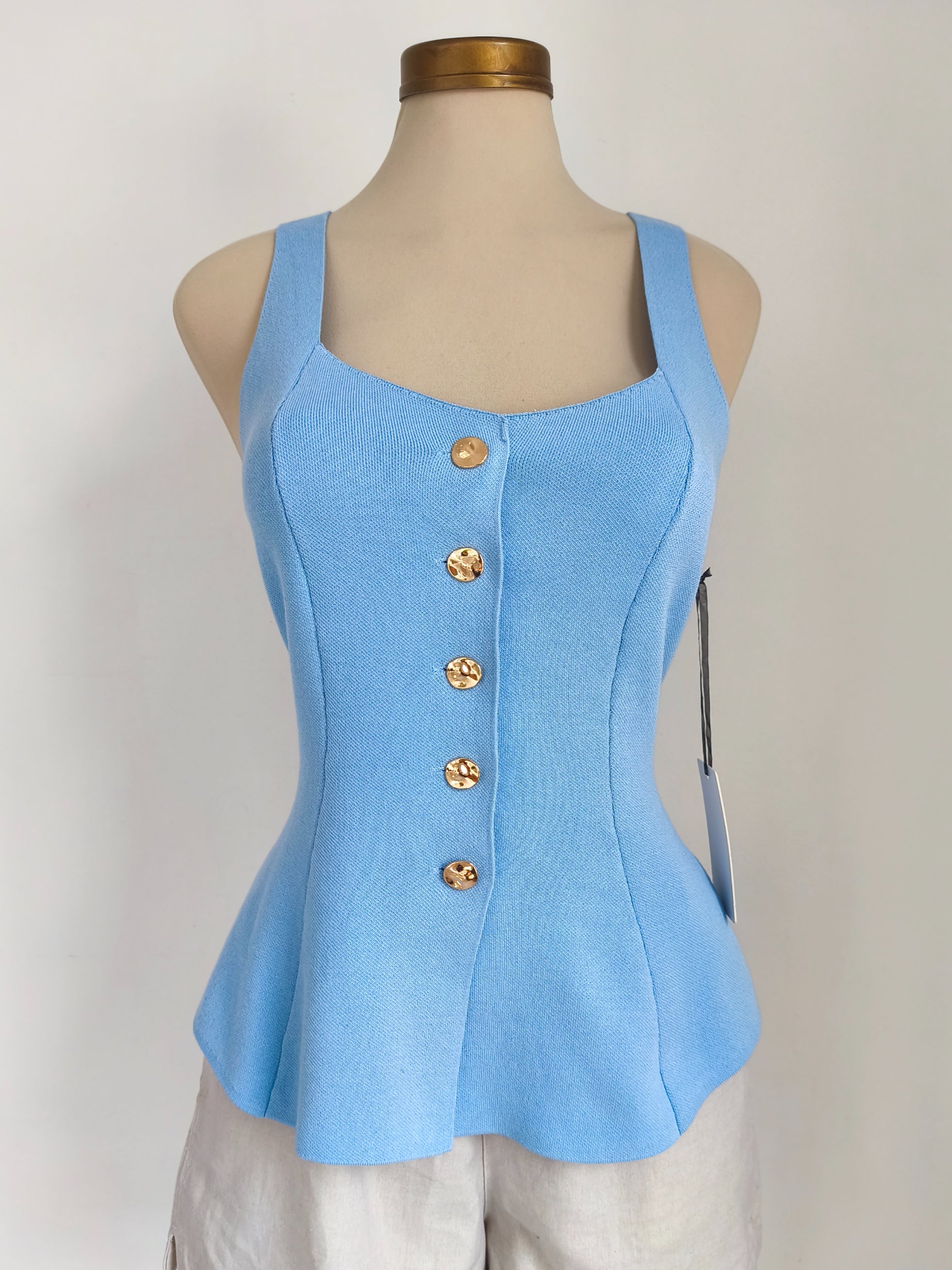 Blusa baby blue sin mangas con botones dorados y peplum